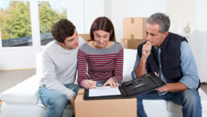 Jovem casal assinando contrato com empresa de mudança.